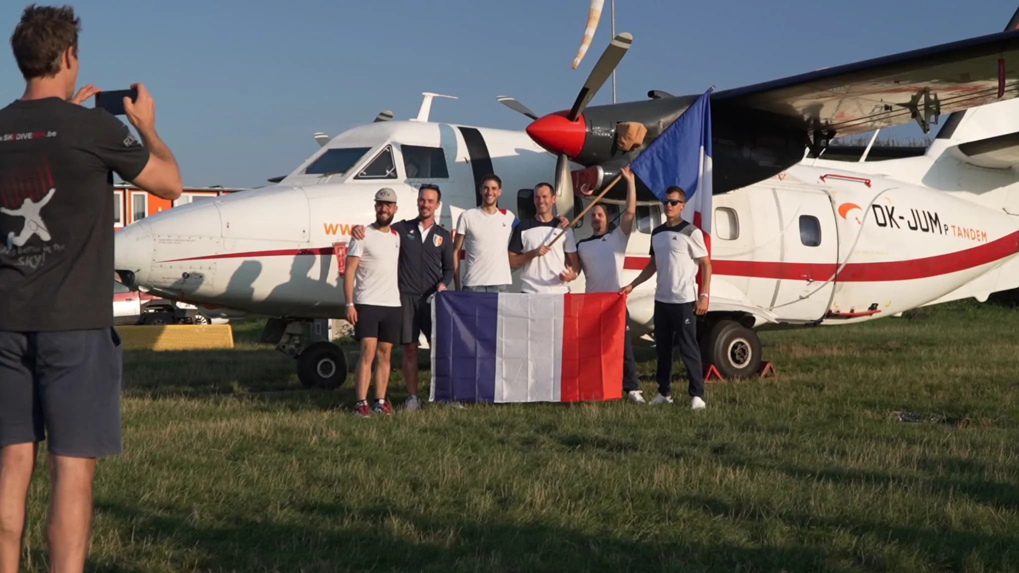 Menschen vor einem weißen Flugzeug mit Fallschirmspringern