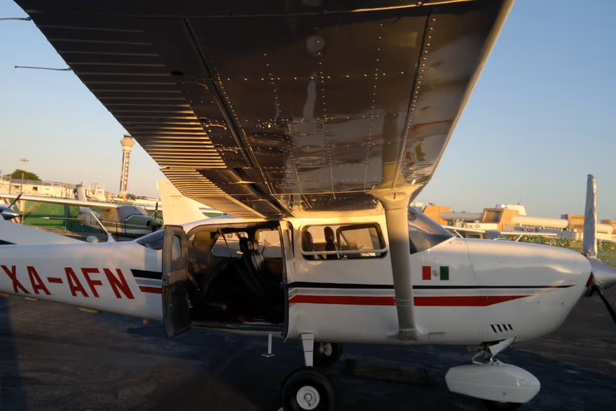 Kleines weißes Cessna-Flugzeug mit geöffneten Türen, in der Abenddämmerung auf dem Flugplatz abgestellt.