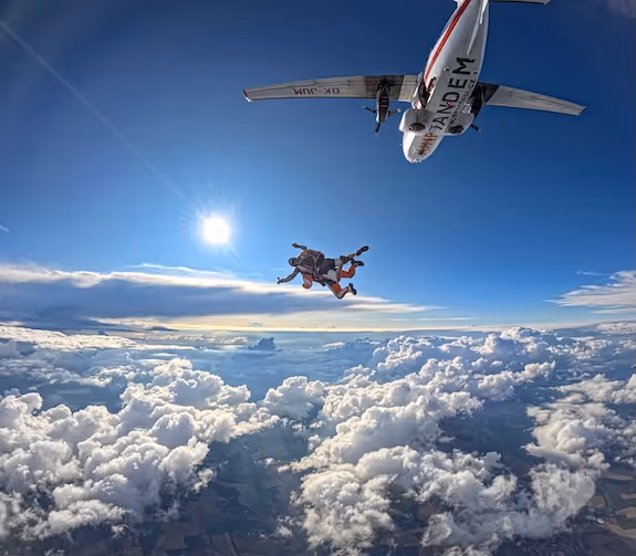 Un instructor tándem y su pasajero saltan del avión y vuelan por el aire.