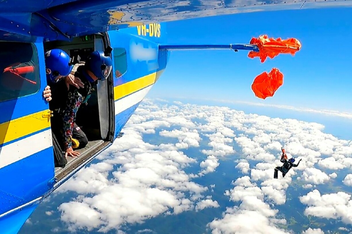 parachutiste suspendu à l'aile d'un avion par son parachute